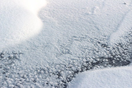 Stunning abstract close-up of sparkling frost crystals on dark ice meeting fresh, bright snow drifts...