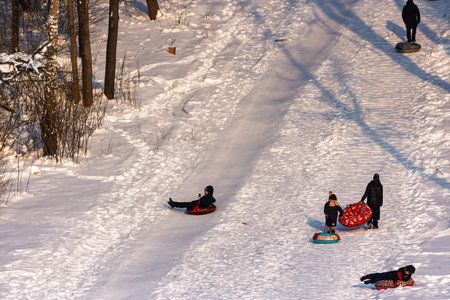 Kids joyfully sledding down a snowy hill on inflatable tubes, creating winter fun and cheerful outdoor recreation: Russia - January 24, 2026のeditorial素材