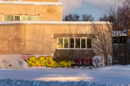 Gritty urban wall with vibrant graffiti brightened by golden winter sunlight over deep snowdrifts: Russia - January 13, 2026のeditorial素材