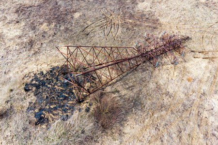 Aerial view of a rusty transmission line support overturned on the ground, dismantling of an obsolete metal structureの写真素材