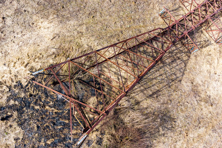 Rusty high-voltage power transmission line support lying on the ground, aerial viewの写真素材