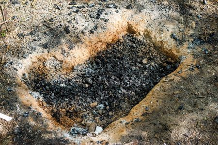 A hole in the ground with coals dug for a fire pitの写真素材