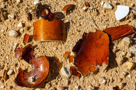 Shards of a broken glass bottle lying on the sandの写真素材