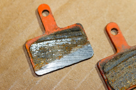 Worn out bicycle brake pads showing metal backing, indicating total wear and need for immediate replacementの写真素材