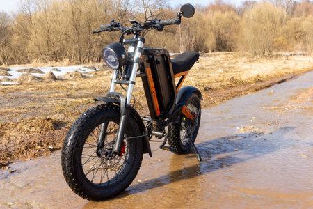 Rugged electric fatbike conquers a flooded rural road amidst melting snow, epitomizing spring...