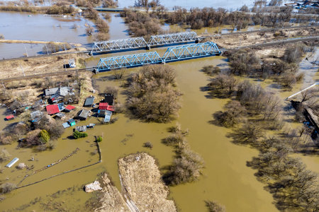 Drone view of flooded countryside during spring floods. Small village and railway bridge over the river