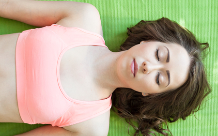 Young Female Stretching On Exercise Mat In Her Roomの写真素材