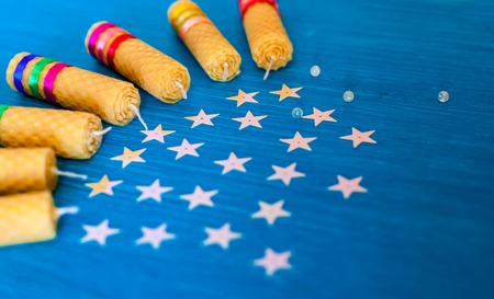 Group twisted candles from natural wax by hand on a background of blue boards and stars. Jewellery...