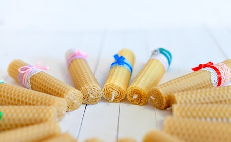 Group candle is in the form of a circle. Candles twisted from natural wax by hand on a background of white boards. Jewellery made of colored laces and ribbons. Rustic Style. Gifts with their own handsの写真素材