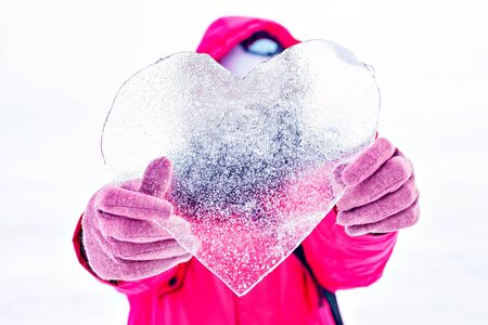 girl holding a piece of transparent ice in the shape of a heart. Ice on Lake Baikal's surface. Winter in Siberiaの写真素材