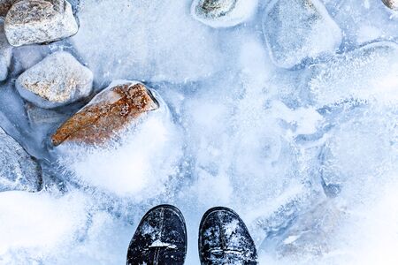 Natural ice background. Frozen lake Baikal. Transparent ice with crack and icebound stones. Legs on iceの写真素材