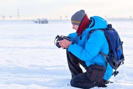 male photographer with camera outdoors in winter snowy dayの写真素材