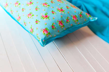 Beautiful blue cushion with floral print on a white wooden background, decoration of interior and exterior of the house. Zone for a comfortable reading and breakfast.の写真素材