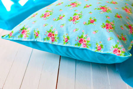 Beautiful blue cushion with floral print on a white wooden background, decoration of interior and exterior of the house. Zone for a comfortable reading and breakfast.の写真素材
