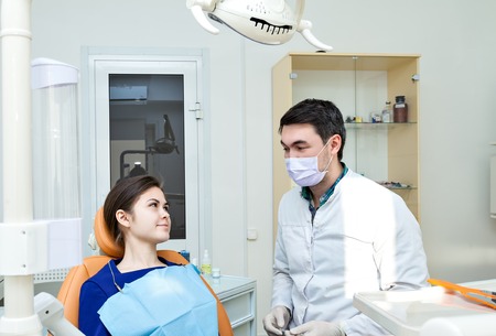 dentist examining a patients teeth in the dentists chair at the dental clinic. Admission to the dentist's office. The doctor in a mask and with the tool.の写真素材