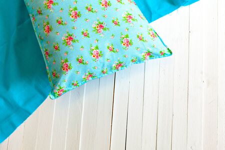 Decoration of the interior and exterior of the house. The zone for comfortable reading of books, and breakfast. Beautiful orange and blue pillows with floral pattern on a white wooden background.の写真素材