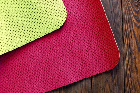 New yoga mat of red and yellow on a wooden background. Facilities for training and yoga. Diagonal. The concept of love to a healthy lifestyle. Weight loss and fitness.の写真素材