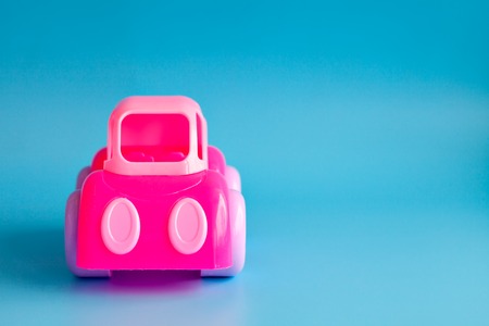 Children's toy plastic pink car on a blue background. Copy space.の写真素材