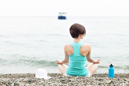 woman meditating in lotus yoga by the sea on the beach