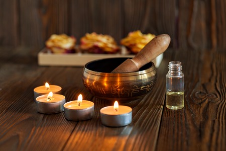 Singing bowl on dark wooden background. Burning candles and oil for aromatherapy and massageの写真素材
