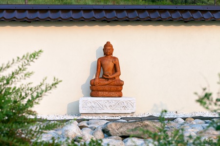 Buddha statue in the setting sun in the garden of stones in the territory of a Buddhist temple. Datsan Rinpoche Bagsha on Bald Mountain in Ulan-Ude, Buryatia, Russia.の写真素材