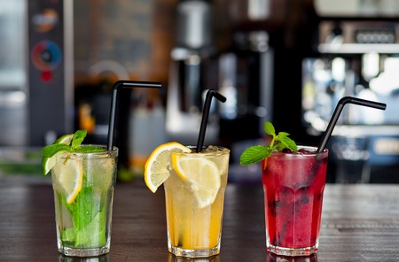 Three different refreshing lemonade with lemon and lime on a background of the bar in the cafe. Summer drink.の写真素材