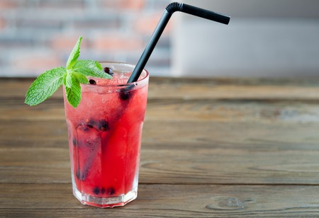 Red refreshing lemonade with berries and ice on a wooden background. Summer drinkの写真素材