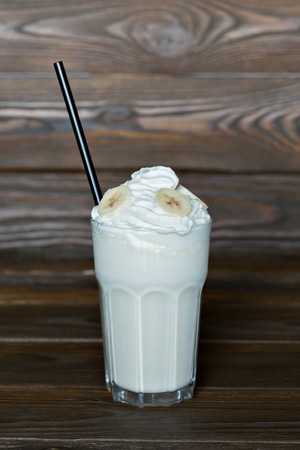 Milk cocktail with banana cream in a tall glass on a wooden backgroundの写真素材