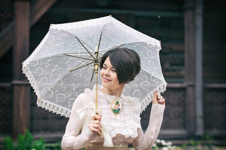 Beautiful young woman in a dress and skruzhevnym zontomportret retro. Vogue Clothing in vintage styleの写真素材