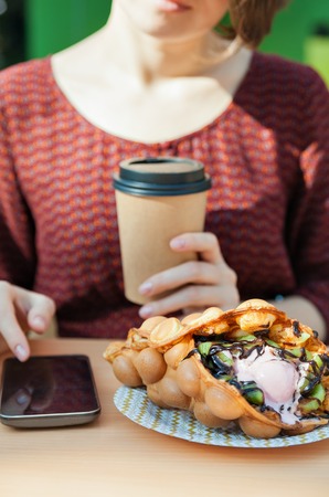 Person with phone and a waffleの写真素材