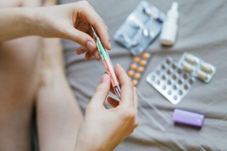 Traditional thermometer for measuring body temperature in hand. pills in hand