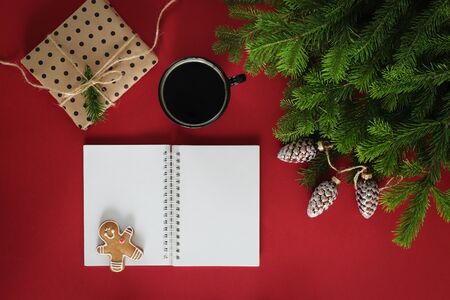 Christmas composition. Christmas decorations, paper empty, gift and drink, fir branches on a red background. Flat lay, top view, copy spaceの写真素材