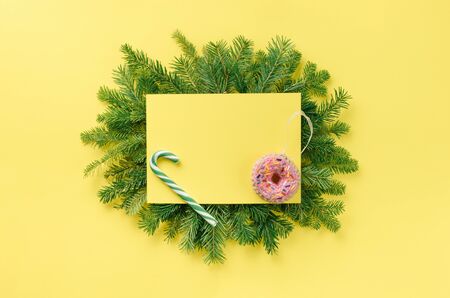 Christmas composition. Christmas decorations, gift on a fir branch on a yellow background. Flat lay, top view, copy spaceの写真素材