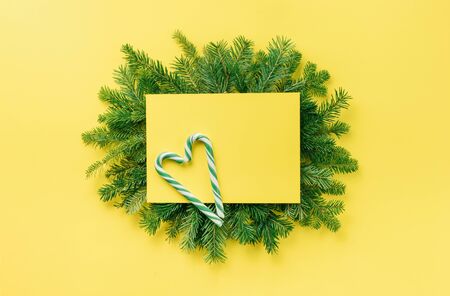 Christmas composition. Christmas decorations, gift on a fir branch on a yellow background. Flat lay, top view, copy spaceの写真素材