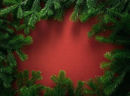 Christmas composition. frame of spruce branches, on a red background. Christmas, winter, new year concept. Flat lay, top view, copy spaceの写真素材