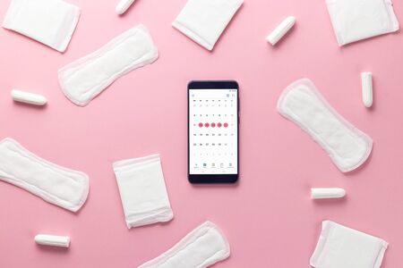 Tampons, feminine sanitary pads and gadget on a pink background. Hygienic care on critical days. menstrual cycle. Caring for womens health. Monthly protection. Flat lay, top view, copy spaceの写真素材