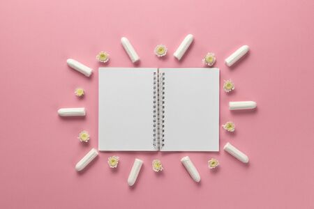Tampons, feminine sanitary pads and empty paper on a pink background. Hygienic care on critical days. menstrual cycle. Caring for womens health. Monthly protection. Flat lay, top view, copy spaceの写真素材