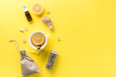 Illness concept. Composition alternative medicine. Herbal tea, ginger and lemon on a yellow background. Flat lay. View from above. Copy spaceの写真素材