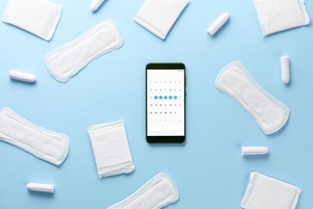 Tampons, feminine sanitary pads and gadget on blue background. Hygienic care on critical days. menstrual cycle. Caring for womens health. Monthly protection. Flat lay, top view, copy spaceの写真素材
