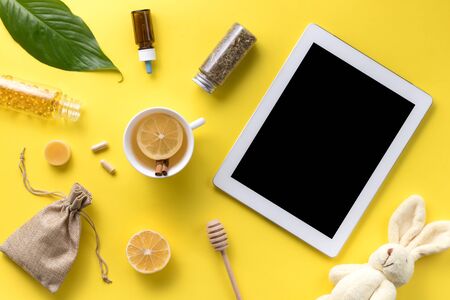 Illness concept. Composition alternative medicine. Herbal tea, ginger, lemon and gadget on a yellow background. Childs health. Flat lay. View from above. Copy spaceの写真素材