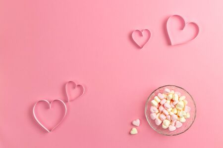 Composition for Valentines Day February 14th. Delicate pink background and a heart cut out of paper. pink heart-shaped marshmallows in a plate. Greeting card. Flat lay, top view, copy space.の写真素材