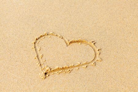 Valentines day on a sunny beach. Heart drawn in the sand, concept of love. Relax on the sandy beach. Copy space.の写真素材