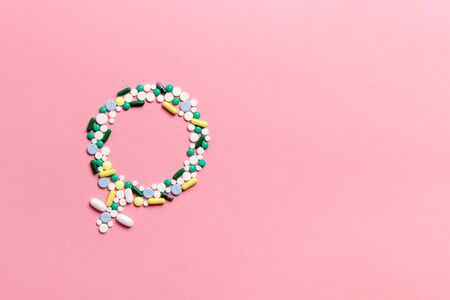 The concept of womens health and gynecology. Gender symbol made of pills on a pink background. Menopause, menstruation or estrogen concept.の写真素材