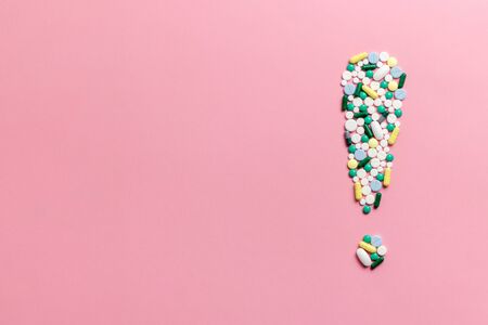 Composition of pills and capsules on a pink background in the form of an exclamation mark. Psychological help. Copy space. View from above. Flat lay.の写真素材