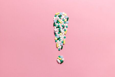 Composition of pills and capsules on a pink background in the form of an exclamation mark. Psychological help. Copy space. View from above. Flat lay.の写真素材