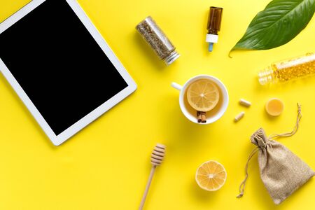 Illness concept. Composition alternative medicine. Herbal tea, ginger, lemon and gadget on a yellow background. Flat lay. View from above. Copy spaceの写真素材