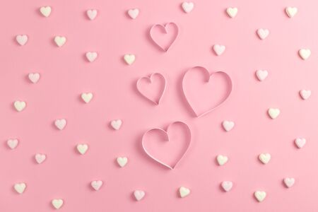 Composition for Valentines Day February 14th. Delicate pink background and a heart cut out of paper. Heart shaped yellow and pink marshmallows. Greeting card. Flat lay, top view, copy spaceの写真素材