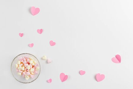 Composition for Valentine's Day February 14th. Delicate composition of pink hearts made of paper and heart-shaped marshmallows on a white background. Greeting card. Flat lay, top view, copy spaceの写真素材