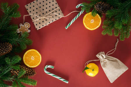 Christmas card. Composition from Christmas decorations, orange and gift, fir branches on a red background. Flat lay, top view, copy space.の写真素材