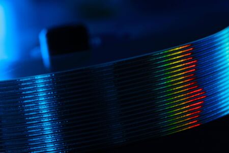 Stack of audio CD and rainbow reflection. Compact disks in blue light. Diagonal viewの写真素材